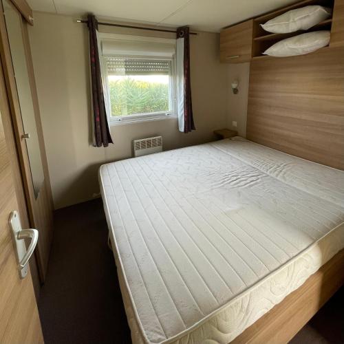 łóżko w małym pokoju z oknem w obiekcie Parc Résidentiel La Listra - Bungalow w mieście Belgodère