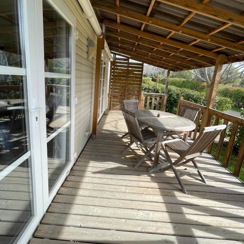 une terrasse couverte en bois avec une table et des chaises. dans l'établissement Parc Résidentiel La Listra - Bungalow, à Belgodère