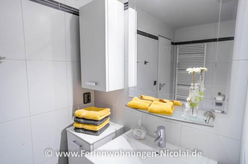 uma casa de banho branca com toalhas amarelas num lavatório em Panorama Schönberger-Strand Appartement 29 em Stakendorfer Strand