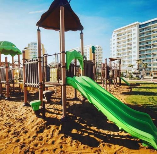 um parque infantil com um escorrega verde na areia em Northern C y p r u s Trikomo, Iskele, Long Beach, Caesar Resort apartment Commodus -SMART TV em Trikomo