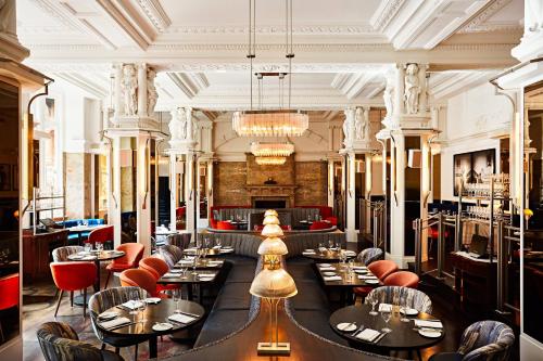 a restaurant with tables and chairs in a room at Kimpton Fitzroy London by IHG in London
