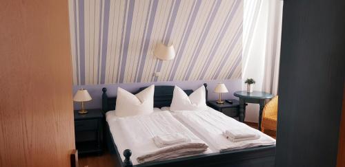 a bedroom with a bed with white sheets and pillows at Restaurant und Pension Zur Nassen Ecke in Wittenbeck
