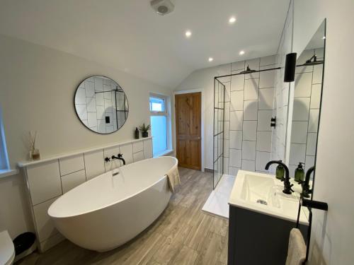 a large white tub in a bathroom with a mirror at TAFFS MEAD HOUSE Central City Location, nr Stadium, Family Friendly in Cardiff