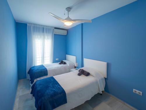 Habitación azul con 2 camas y ventilador de techo. en Center Luxury fjhomefj, en Jerez de la Frontera