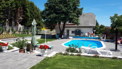 a backyard with a swimming pool and a house at Főnix Apartmanház in Vonyarcvashegy
