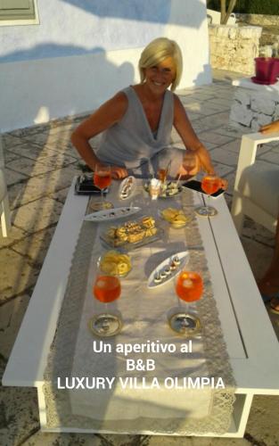 a woman sitting at a table with food on it at B&B Luxury Villa Olimpia Home Restaurant in Selva di Fasano