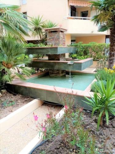 un jardin avec une fontaine en face d'un bâtiment dans l'établissement Les Orangers de Santa Lucia, vue mer et port, St Raphaël, à Saint-Raphaël
