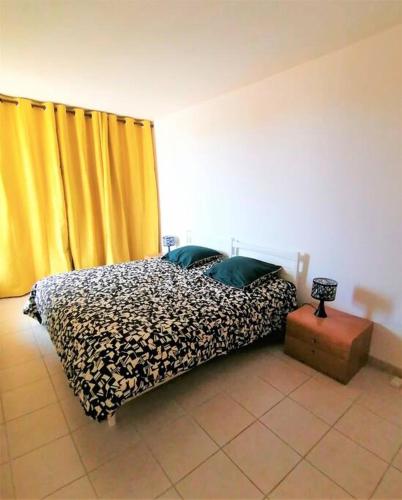 - une chambre avec un lit et un rideau jaune dans l'établissement Les Orangers de Santa Lucia, vue mer et port, St Raphaël, à Saint-Raphaël