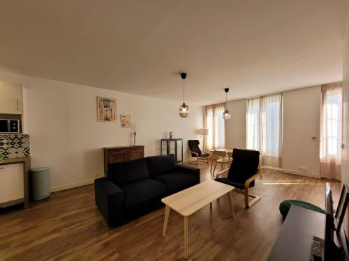 un salon avec un canapé noir et une table dans l'établissement Duplex cosy & lumineux en plein centre bourg, à Macau