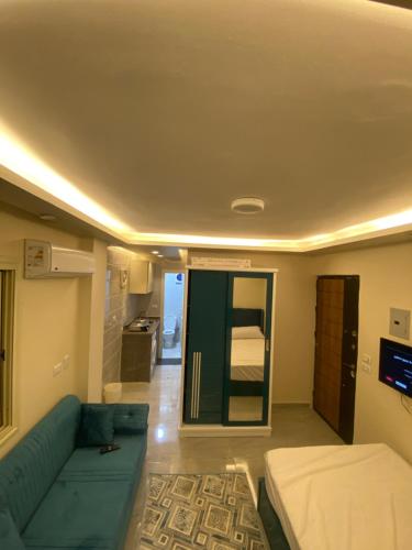 ein Wohnzimmer mit einem blauen Sofa und einem Bett in der Unterkunft استديو in Madinat as-Sadis min Uktubar