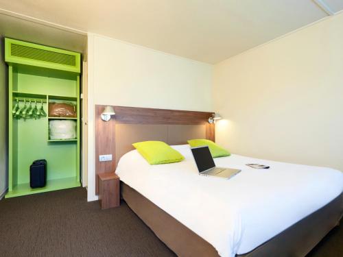 a bedroom with a large bed with a laptop on it at Campanile Nantes ~ Rezé Aéroport in Rezé