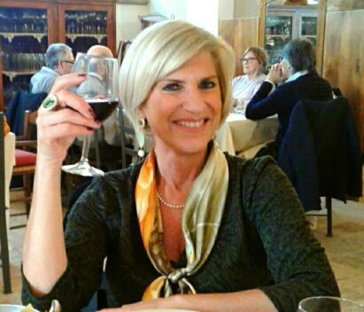 a woman sitting at a table holding a glass of wine at B&B Luxury Villa Olimpia Home Restaurant in Selva di Fasano