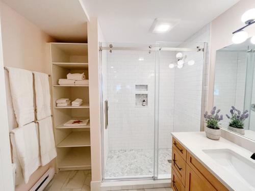 a white bathroom with a shower and a sink at Ned's Landing at Spry Point in Little Pond