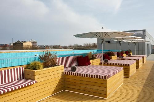 une terrasse avec bancs et parasols et une piscine dans l'établissement The Social Hub Toulouse, à Toulouse