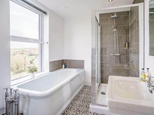 a white bathroom with a tub and a sink at Gwbert Holiday Cottages, Green Meadow in Cardigan