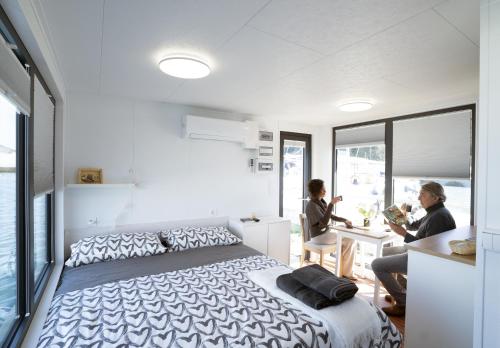 a bedroom with a bed and two people sitting at a table at ALMALO Floating House - Casa Galleggiante in Procida