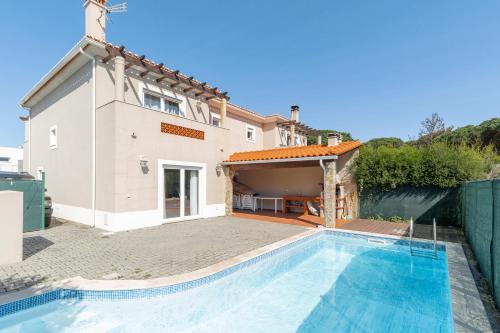 a villa with a swimming pool in front of a house at Vila Pérola da Lagoa in Vau