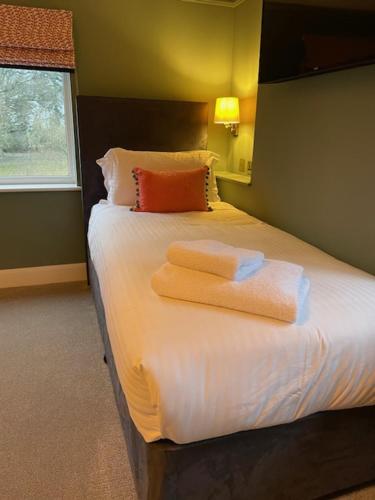 a bedroom with a bed with two towels on it at Cottesmore Hotel Golf & Country Club in Crawley