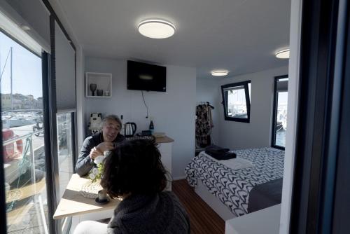 ALMALO Floating House - Casa Galleggiante في بروسيدا: امرأة تجلس على طاولة في غرفة