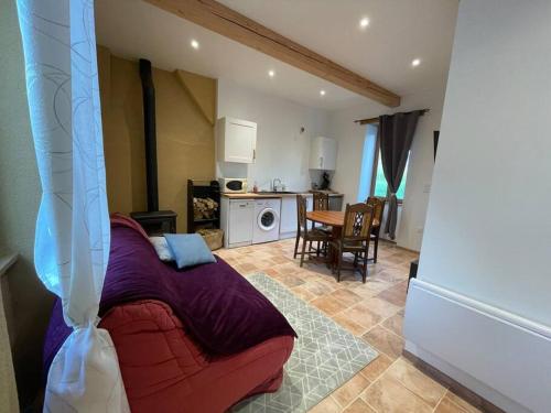 a living room with a red couch and a kitchen at Maisonnette de campagne 70m2 in Lartigue