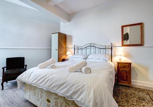 ein Schlafzimmer mit einem Bett mit weißer Bettwäsche und einem Stuhl in der Unterkunft Oddicombe Hall Flat 2 in Torquay