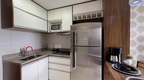 eine Küche mit einem Edelstahlkühlschrank und weißen Schränken in der Unterkunft Apartamento Moderno no DF Plaza in Brasilia