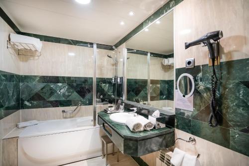 uma casa de banho com uma banheira e um lavatório e uma banheira em Abba Madrid em Madrid