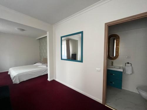 ein Schlafzimmer mit einem Bett und ein Badezimmer mit einem Spiegel in der Unterkunft Eden Boutique Accommodation in Bukarest