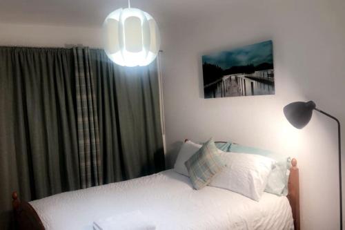 a bedroom with a bed with a lamp and a window at Entire One Bedroom Apartment Near Stratford in London