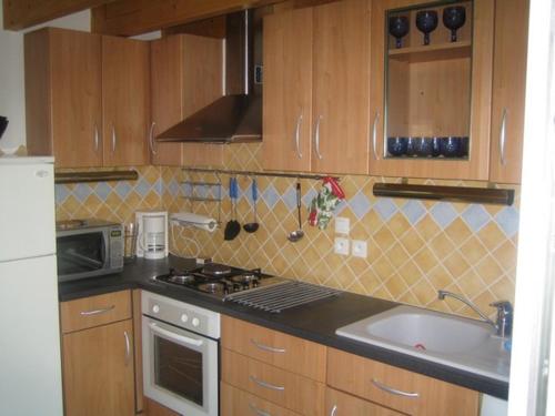 - une cuisine avec des placards en bois, une cuisinière et un évier dans l'établissement Bretagne, à Pleubian