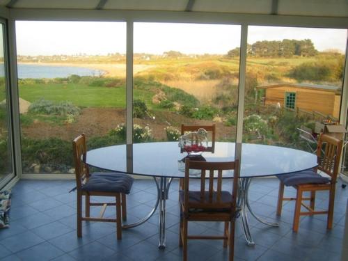 une table et des chaises dans une pièce avec une grande fenêtre dans l'établissement Bretagne, à Pleubian