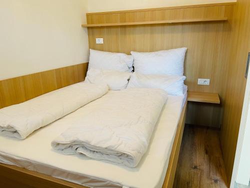 1 cama con sábanas blancas y almohadas en una habitación en Residence Bichler en Merano