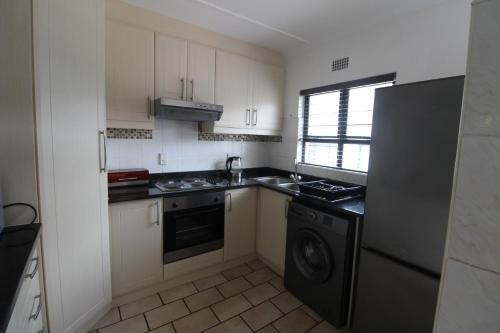 a kitchen with white cabinets and a black refrigerator at Windsor Place 6 in Uvongo Beach