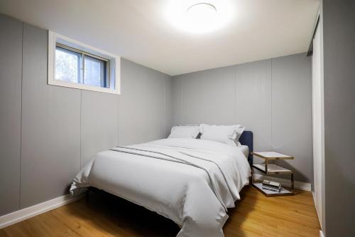 ein weißes Schlafzimmer mit einem Bett und einem Fenster in der Unterkunft Modern Rustic Guest Suite w/ Gym&Pool Near Toronto in Richmond Hill