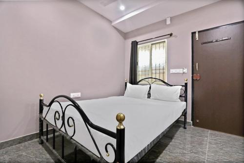 a bedroom with a bed with white sheets and a door at SPOT ON Krishnaa Comforts Near Cubbon Park in Bangalore