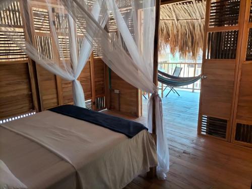 a bedroom with a bed and a hammock in a room at Bungalow Palmar del Viento in Moñitos