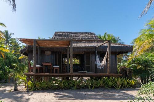 a small hut on the beach with palm trees at Oka Maraú I Charming Bungalows in Marau