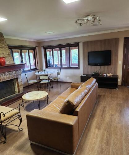 a large living room with a couch and a tv at Pousada Bliss House - Opções de suites com hidromassagem in Campos do Jordão