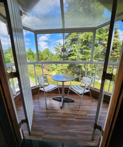 a screened in porch with a table and chairs at Pousada Bliss House - Opções de suites com hidromassagem in Campos do Jordão