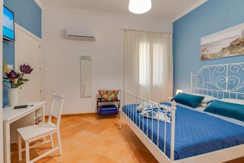 ein blaues Schlafzimmer mit einem Bett und einem Schreibtisch in der Unterkunft Namuri Rooms in Sciacca
