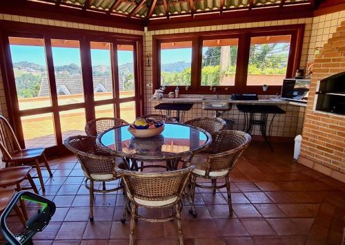 een eetkamer met een tafel, stoelen en ramen bij Pousada Bliss House - Opções de suites com hidromassagem in Campos do Jordão
