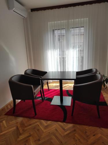 a dining room with a table and chairs on a red rug at Una La Unica in Bihać