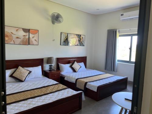 ein Hotelzimmer mit 2 Betten und einem Fenster in der Unterkunft Hotel Hòa Bình in Bình Châu