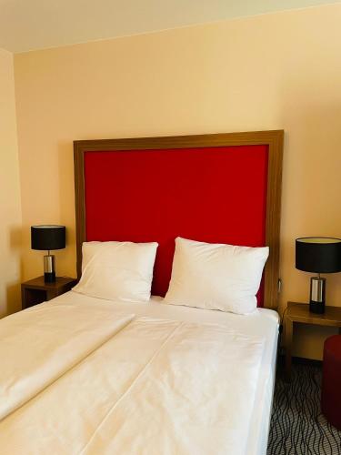 a bedroom with a large bed with a red headboard at Point Hotel Apartments and Rooms in Dresden