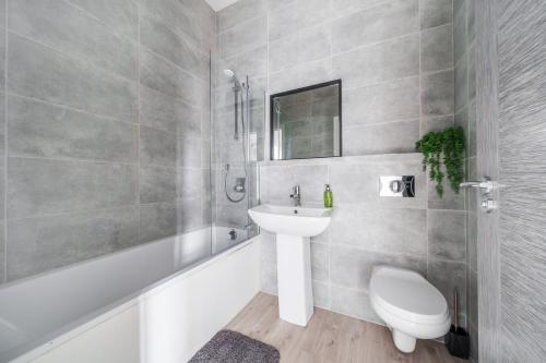 a bathroom with a sink and a toilet and a tub at The Old Town Hall - 12 in Staines