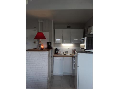 a kitchen with white cabinets and a red lamp at Parenthèse Bleue à Cabourg in Cabourg