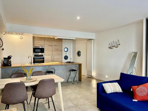 een woonkamer met een blauwe bank en een keuken bij Le Cours Ladauge in La Rochelle