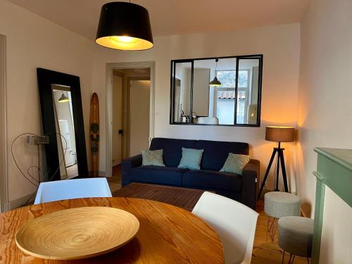 sala de estar con mesa y sofá azul en Dormir À La Rochelle 1 avec Parking, en La Rochelle