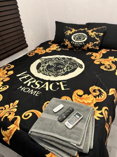 圣胡安Satisfaction的一张带黑色金色毯子和遥控器的床