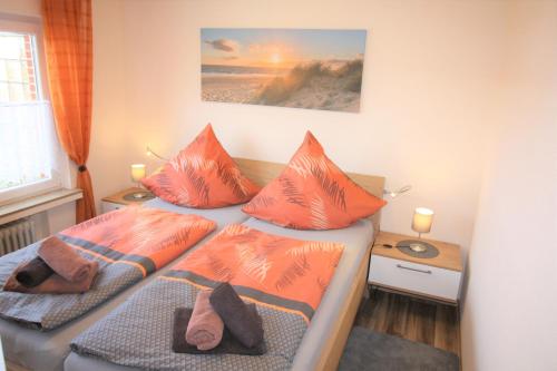 um quarto com 2 camas com almofadas laranja em Haus Ingrid em Norddeich
